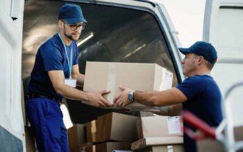 Delivery men loading carboard boxes in a van while getting ready for the shipment.